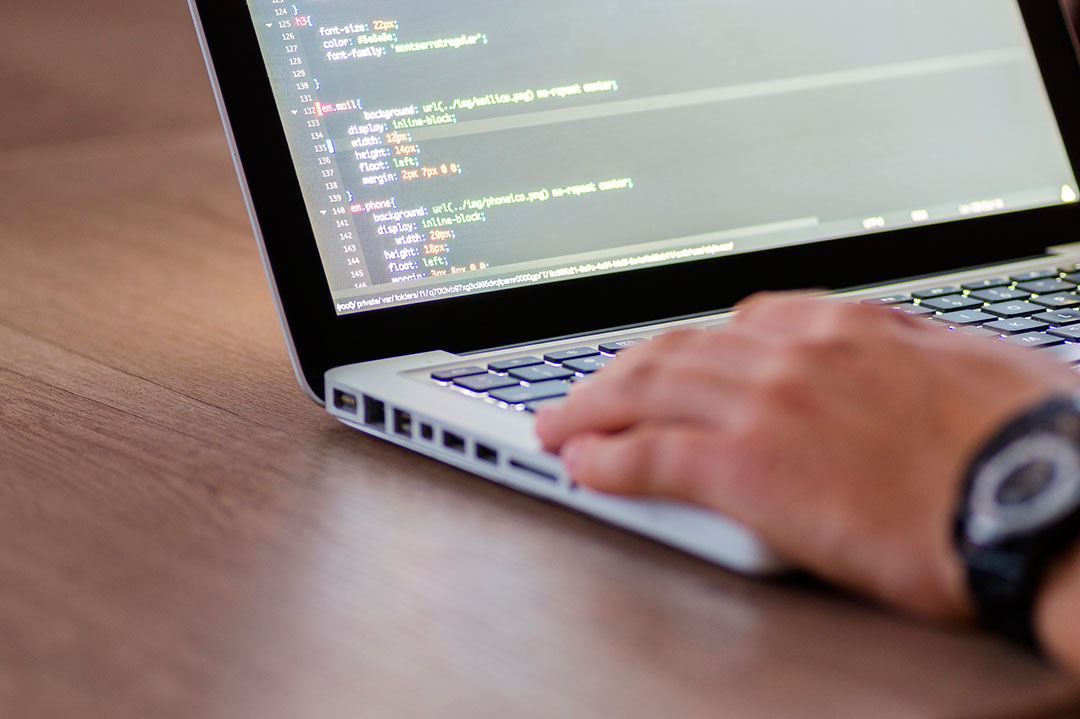 Nootebook em cima de uma mesa com um homem programando